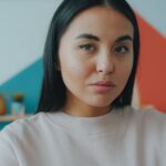 Close-up portrait of a woman indoors with a vibrant geometric background.